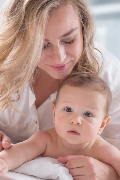 Mother and baby boy son playing on a white bed. Mothers tenderne — Stock Photo, Image