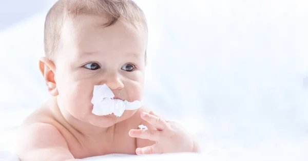 Funny portrait of cute toddler boy lying on bed and trying to ea — Stock Photo, Image