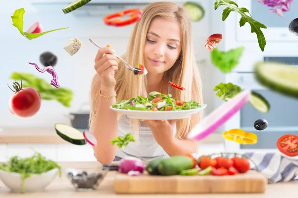 Joven chica rubia feliz comiendo ensalada saludable de rúcula espinaca — Foto de Stock