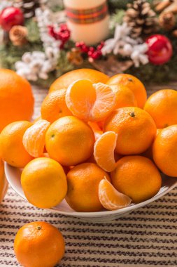 Mandalina ve portakallar yeni çelenkle birlikte noel masasında.