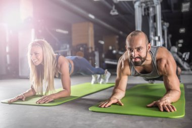 Spor çifti fitness merkezinde kalas egzersizi yapıyor. Anne!