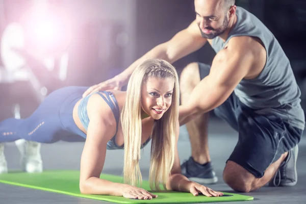 Coach trainer en sportvrouw doen plank in de sportschool — Stockfoto