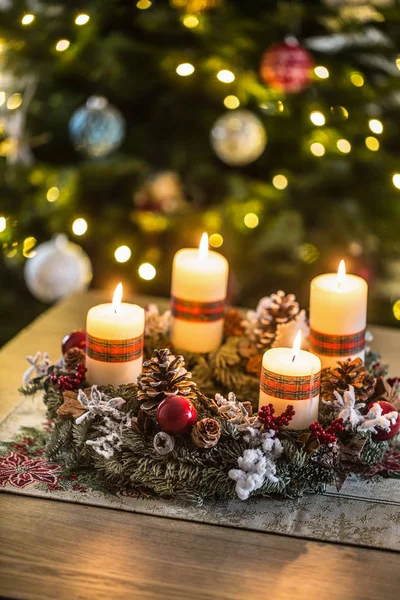 Guirlanda do Advento com quatro velas brancas queimando bola de Natal e decorações em um fundo de madeira com atmosfera festiva — Fotografia de Stock