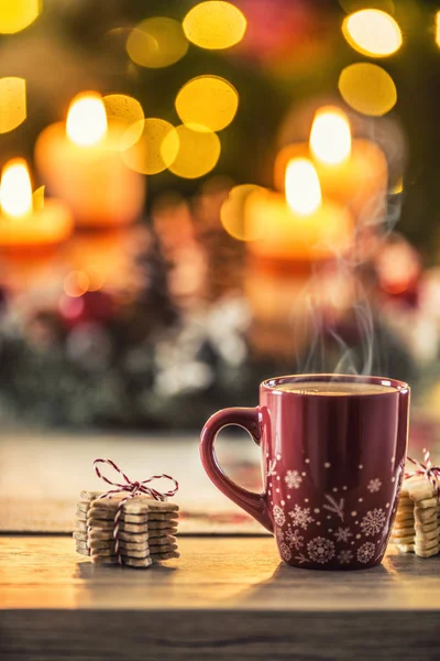 크리스마스 커피와 생동감넘치는 탁자 위에 백라이트 가 배경에 있는 화환 — 스톡 사진