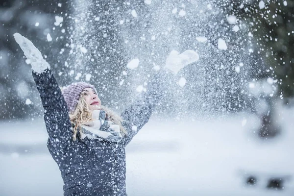 Young woman in warm clothes is having fun out of the snow — 스톡 사진