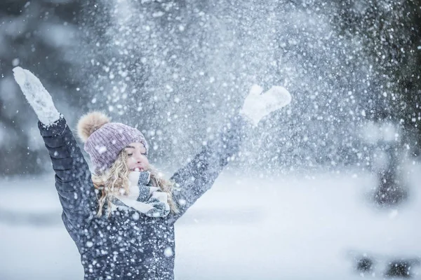 Young woman in warm clothes is having fun out of the snow