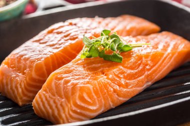 Dökme demir tavada servis edilen taze çiğ somon filetoları.