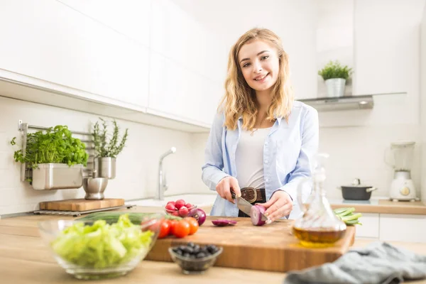 Giovane ragazza bionda felice preparare insalata sana in cucina di casa — Foto Stock