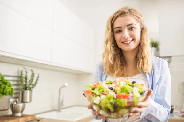 Giovane ragazza bionda felice preparare insalata sana in cucina di casa — Foto Stock