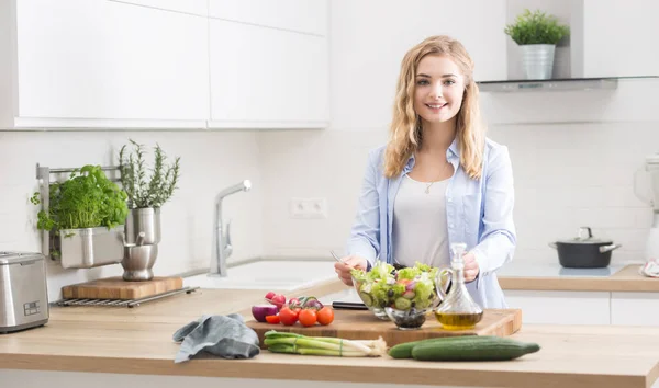 Giovane ragazza bionda felice preparare insalata sana in cucina di casa — Foto Stock