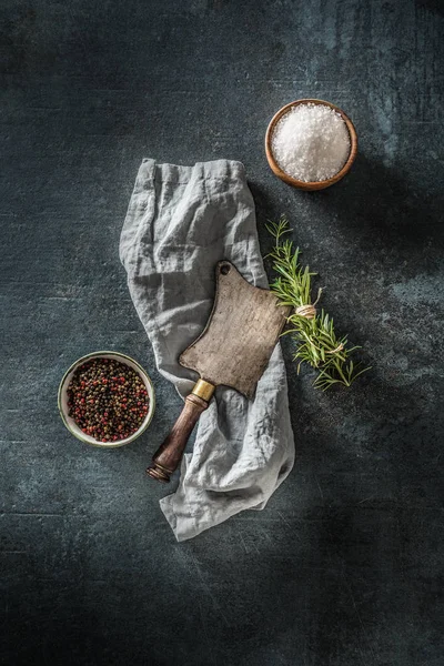 Carniceiro velho em placa de concreto escuro com ervas sal e pimenta — Fotografia de Stock