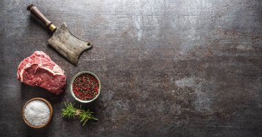 Et satırlı çiğ biftek ve koyu beton arka planda tuz biberi.