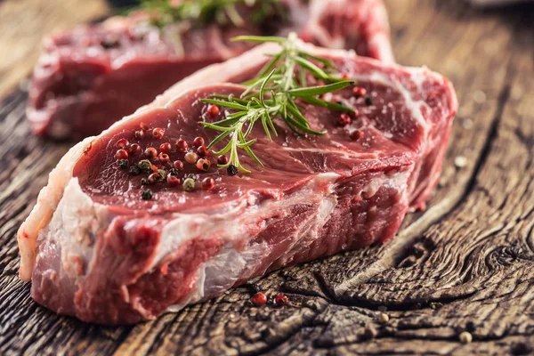 Nötkött Rib Eye biff med salt peppar och rosmarin på träbord — Stockfoto