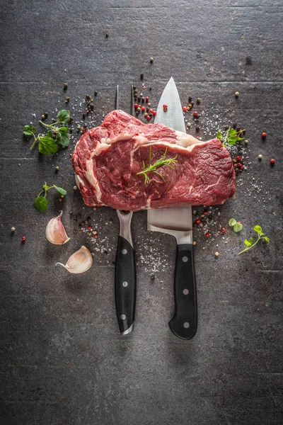 Rå biff med gaffel och kniv salt peppar och örter på mörk betong bakgrund — Stockfoto
