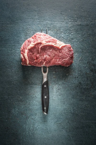 Raw beef steak with fork on dark concrete background — 스톡 사진