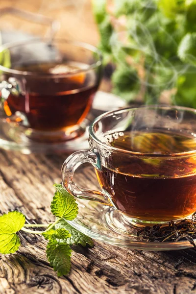 A cup of melissa tea with herbs on wooden table — Stock Photo, Image