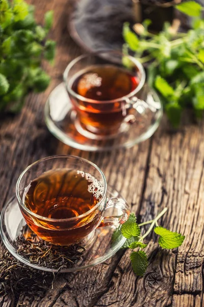 A cup of melissa tea with herbs on wooden table — Stock Photo, Image