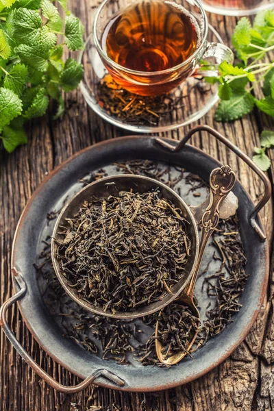 Dried tea leaves in bowl on rustic wooden table — Stock Photo, Image