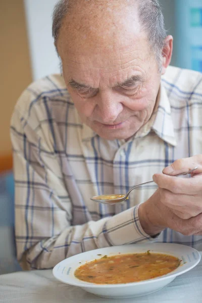 Elderly man with Parkinsons disease holds spoon in both hands — Stock Photo, Image