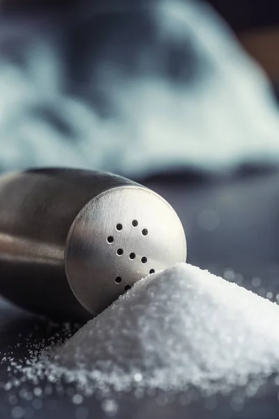 Spilled salt with staniless salt shaker - Closeup