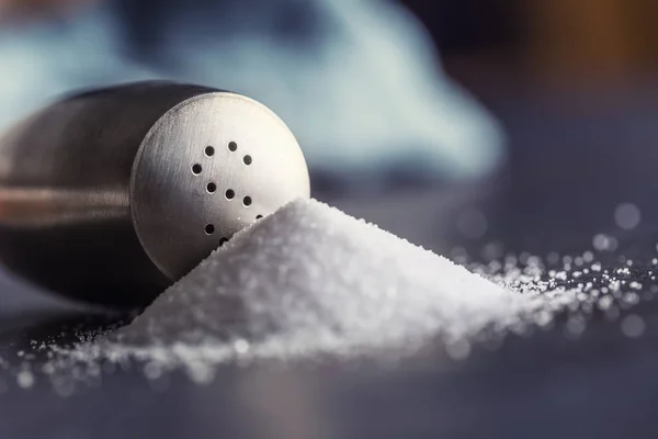 Spilled salt with staniless salt shaker - Closeup