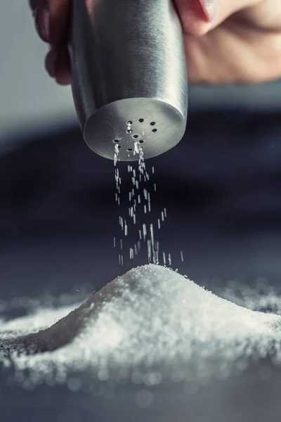 Kvinnlig hand häller salt från staniless salt shaker — Stockfoto