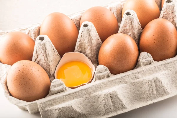 Свіжі курячі яйця в паштетному лотку з розбитим яйцем — стокове фото