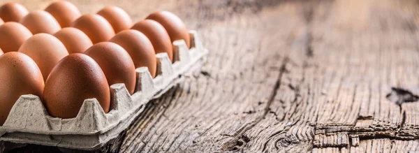 Курячі яйця в картонній коробці на сільському дерев'яному столі — стокове фото