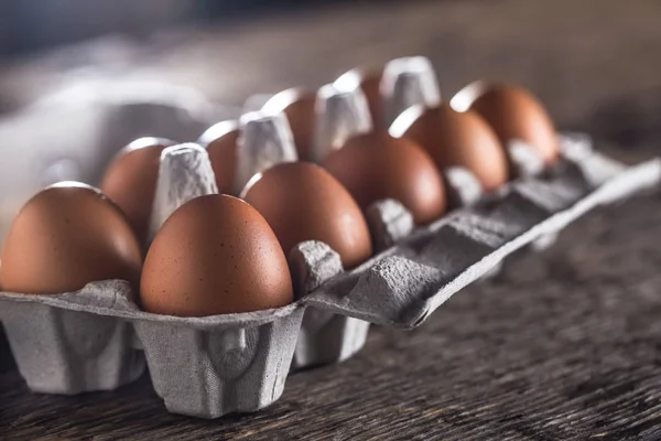 Chicken eggs in carton box on rustic wooden table