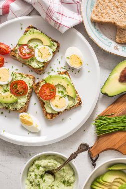 Healthy breakfast from toasts with avocado spread guacamole egg tomato and chives.