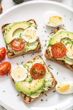 Healthy breakfast from toasts with avocado spread guacamole egg tomato and chives.