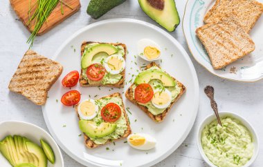 Healthy breakfast from toasts with avocado spread guacamole egg tomato and chives.