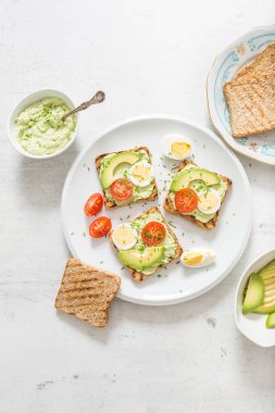 Healthy breakfast from toasts with avocado spread guacamole egg tomato and chives.