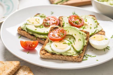 Healthy breakfast from toasts with avocado spread guacamole egg tomato and chives.
