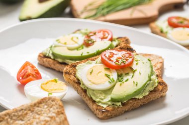 Healthy breakfast from toasts with avocado spread guacamole egg tomato and chives.
