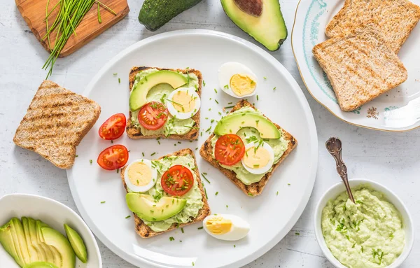 Healthy breakfast from toasts with avocado spread guacamole egg tomato and chives. — Stock Photo, Image