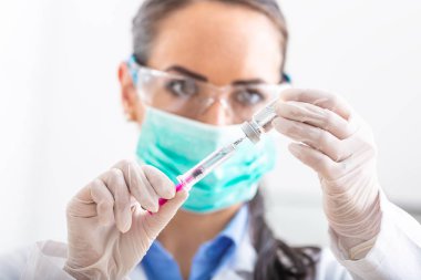 Şırınga iğnesi ve medicin ampulü ile çalışan kadın doktor