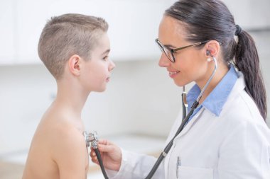 Genç doktor çocuk doktoru, Steth 'le birlikte erkek hastayı muayene ediyor.