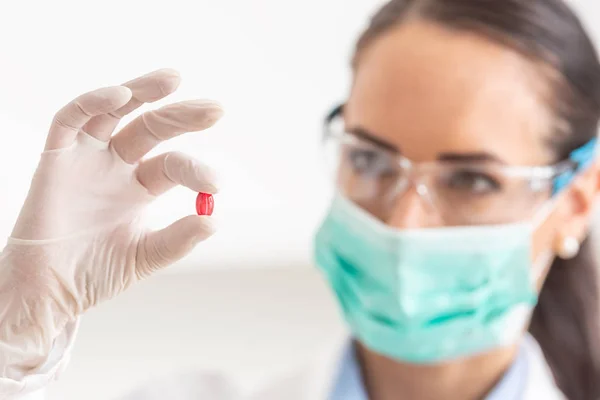 Joven científica sosteniendo una píldora roja - primer plano — Foto de Stock
