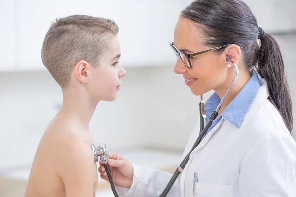 Молодая врач-педиатр осматривает мальчика, больного Стивеном — стоковое фото