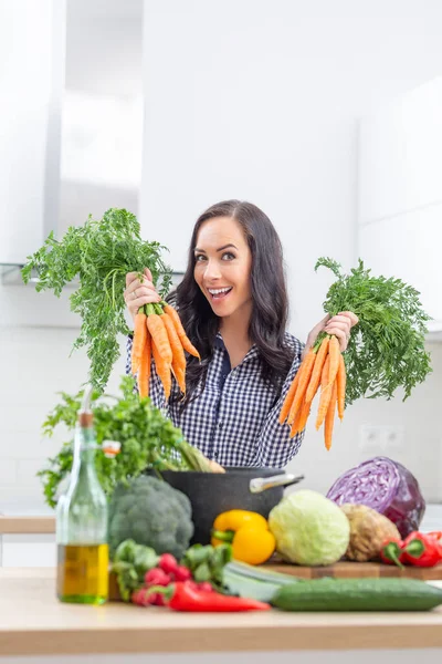 在厨房里拿着新鲜胡萝卜的爱开玩笑的年轻女人 饮食蔬菜和健康概念 — 图库照片