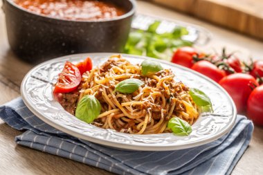 İtalyan spagetti bolonez peynirli ve fesleğenli beyaz tabakta servis edilir.