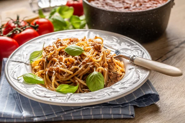 Bolonhesa de macarrão italiano servido em prato branco com queijo parmesão e manjericão — Fotografia de Stock