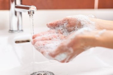 Banyoda su ve sıvı sabunla ellerini yıkamak. Hijyen karşıtlığı virüs konsepti