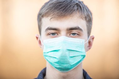 Yüzünde koruyucu maske olan genç bir adam. Virüs tozu ve sise karşı koruma. Coronavirus Covid-19 konsepti.