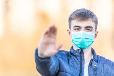 Koruyucu maskeli genç adam jest yapıyor. Coronavirus covid-19 'u durdurun..