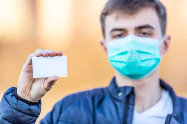 彼の顔に保護マスクを持つ若い男は 空の白いカードを保持 ウイルスのほこりやスモッグから保護します コロナウイルス Covid 19のコンセプト — ストック写真