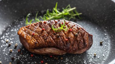 Seramik tavada tuzlu ve biberiyeli ördek göğsü.