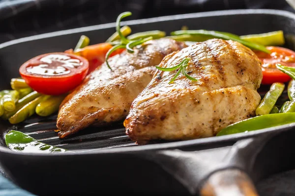 Gezond thuis koken, grillpan kip met groene erwten en tomaten en rozemarijn close-up — Stockfoto