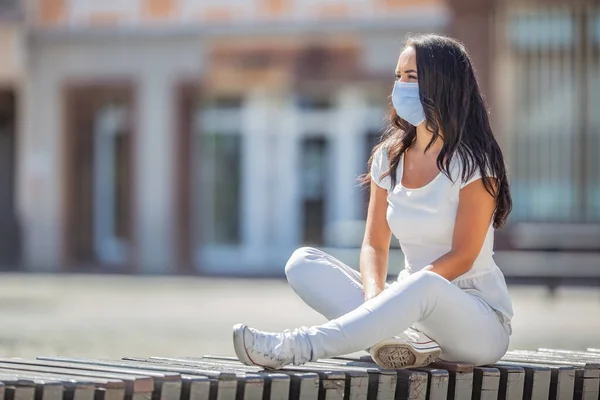 良い女の子は一人で座っベンチで市内中心部に顔マスクを身に着けている間にCovid 19パンデミック — ストック写真
